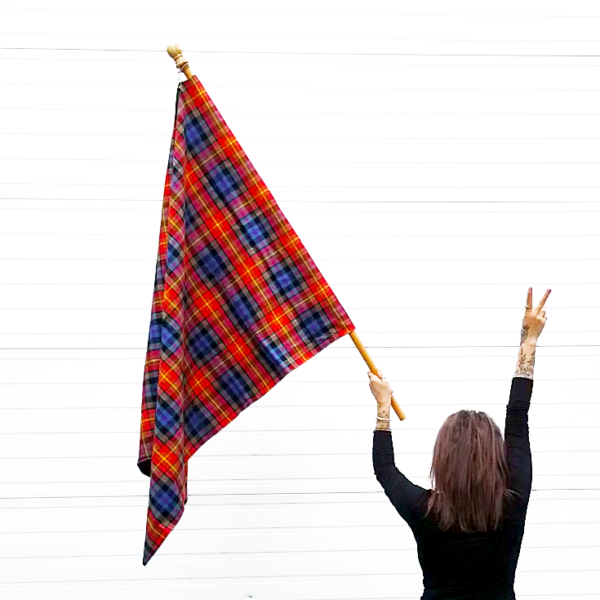 A woman proudly waving an LGBT Pride Tartan Flags - Homespun Wool Blend in the air.