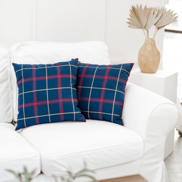 Two plaid throw pillows on a couch in a living room.