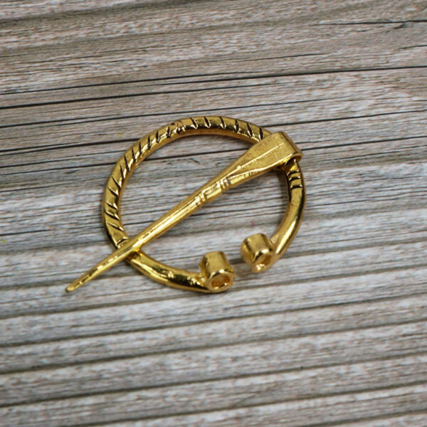 A mini Mini Penannular Brooch on a wooden surface.
